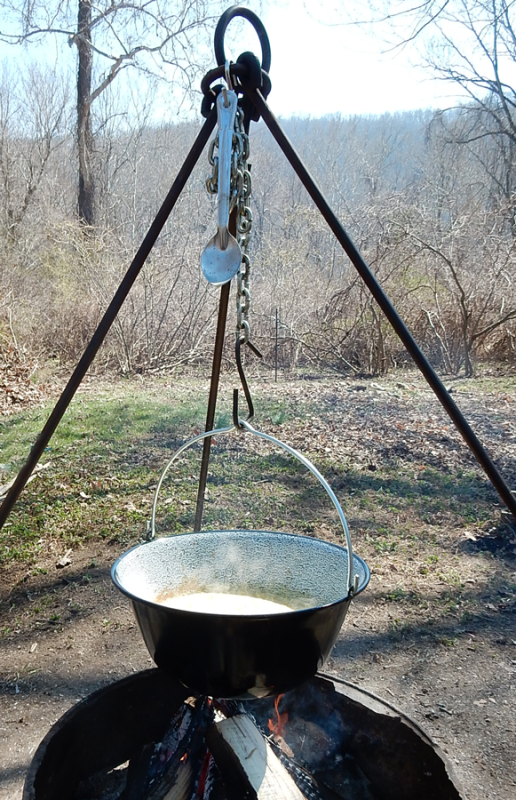 Cooking food over a campfire using a hanging stand while camping in the forest